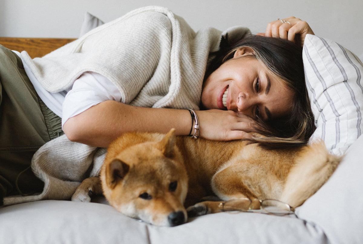 Woman gently embracing her dog on a cream sofa — Charlotte Collective, Style With a Purpose